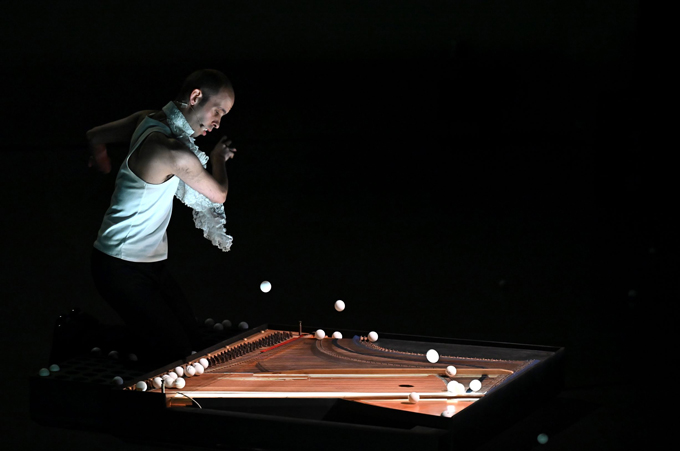 Julien_2023_Page_01 Photographie du spectacle Julien représentant le comédien lancant des balles sur les cordes d'un piano